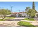 A charming single-story home boasts a red tile roof, lush green lawn, and a welcoming curb appeal at 701 W Cambridge Ave, Phoenix, AZ 85007