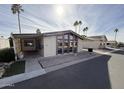 Tan single-wide manufactured home with carport, palm trees, and driveway at 9302 E Broadway Rd # 24, Mesa, AZ 85208