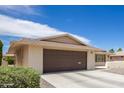 Front view of a ranch home with a brown garage door and landscaping at 10714 W Saratoga Cir, Sun City, AZ 85351