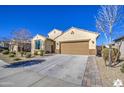 Tan house with a two-car garage and neatly landscaped yard at 18216 W Foothill Dr, Surprise, AZ 85387