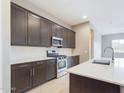 Modern kitchen featuring dark brown cabinets, white countertops, and stainless steel appliances at 19583 W Cheery Lynn Rd, Buckeye, AZ 85396