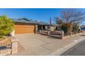 Brick house with a wooden garage door, neat landscaping, and a flag displayed at 5210 W Ironwood Dr, Glendale, AZ 85302