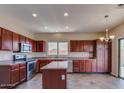 Kitchen with stainless steel appliances, dark wood cabinets, tile floors, and an island at 6102 S 37Th Ln, Phoenix, AZ 85041