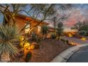 Desert landscaping with lighting accents this beautiful home's exterior at dusk at 6251 E Bramble Berry Ln, Cave Creek, AZ 85331