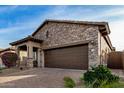 Stone house with brown garage door and manicured landscaping at 8729 E Indigo St, Mesa, AZ 85207