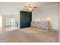 Living room with neutral carpeting, a stone accent wall, and ceiling fan at 9916 E Dolphin Cir, Mesa, AZ 85208