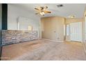 Spacious living room with neutral walls and carpet, a stone accent wall and ceiling fan at 9916 E Dolphin Cir, Mesa, AZ 85208