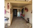 Covered entryway with decorative door, red flower pots, and whimsical decor at 10544 W Campana Dr, Sun City, AZ 85351