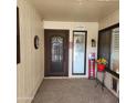 Home entryway with an ornate door and sidelights, welcome decor and red flowers at 10544 W Campana Dr, Sun City, AZ 85351