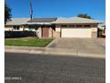 Single story home with solar panels, landscaped lawn, and a two-car garage at 10544 W Campana Dr, Sun City, AZ 85351