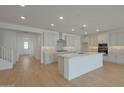 Open-concept kitchen with a center island, stainless steel appliances, and light wood-look flooring at 23136 E Watford Dr, Queen Creek, AZ 85142