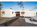 Contemporary exterior showcasing the modern design, desert landscaping, and a well-lit walkway leading to the entrance at 8255 E Morgan Trl, Scottsdale, AZ 85258