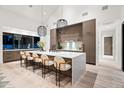 Modern kitchen with waterfall island, pendant lighting, and seating for six at 8255 E Morgan Trl, Scottsdale, AZ 85258