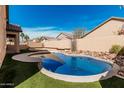Backyard oasis with a refreshing pool, artificial grass, and block wall at 13550 W Port Au Prince Ln, Surprise, AZ 85379