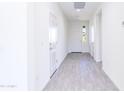 Bright hallway featuring modern gray flooring and white walls leading to the front door at 17469 N 66Th Ave, Glendale, AZ 85308