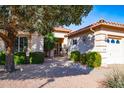 Inviting home entrance with manicured landscaping, desert rock and mature trees at 25440 S Flame Tree Dr, Sun Lakes, AZ 85248