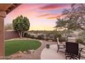 Landscaped backyard with circular putting green, patio furniture, and a beautiful sunset at 25802 N Hackberry Dr, Phoenix, AZ 85083