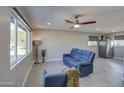 Bright living room featuring a comfortable blue reclining sofa and tile flooring at 6323 N 65Th Dr, Glendale, AZ 85301