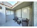 Small patio with two wicker chairs and a small table at 10115 E Mountain View Rd # 2022, Scottsdale, AZ 85258
