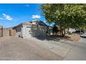 Exterior view of a well-maintained home with a 2-car garage and a mature shade tree in the front yard at 13022 W Surrey Ave, El Mirage, AZ 85335