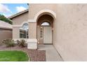 Inviting front entryway with an arched doorway, decorative door, and desert landscaping at 5102 E Charleston Ave, Scottsdale, AZ 85254