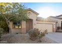 Tan house with a two-car garage and landscaping at 3929 W Glacier Ct, Anthem, AZ 85086