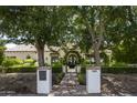 House exterior showcasing a classic design, mature trees, and a brick walkway at 7305 E Royal Palm Rd, Scottsdale, AZ 85258