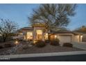 Tan house with a three-car garage and desert landscaping at 11754 E Mariposa Grande Dr, Scottsdale, AZ 85255