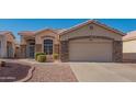 Tan house with stone facade and a two-car garage at 19810 N 90Th Ln, Peoria, AZ 85382