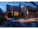 Desert landscape and single-story home with tan stucco exterior, and warm lighting at 9574 E Chuckwagon Ln, Scottsdale, AZ 85262