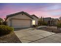 Inviting single-story home featuring a spacious driveway, a two-car garage and mature desert landscaping at 14033 W Two Guns Trl, Surprise, AZ 85374