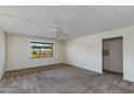 Bright living room with plush carpeting, neutral walls, a ceiling fan, and a view of the serene outdoors at 4201 E Camelback Rd # 25, Phoenix, AZ 85018