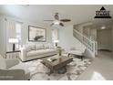 Bright living room featuring neutral décor, a ceiling fan, and a staircase; a harmonious blend of style at 4933 E Meadow Mist Ln, San Tan Valley, AZ 85140