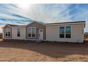 Three-bedroom manufactured home with a tan and beige exterior, numerous windows and a front door at 7710 S 350Th Ave, Tonopah, AZ 85354