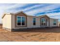 Manufactured home with light tan and brown exterior, multiple windows, and a front door at 7710 S 350Th Ave, Tonopah, AZ 85354