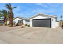 White brick house with gray garage door and mature palm trees at 4242 E Sacaton St, Phoenix, AZ 85044