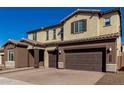 Two-story house with brown and beige exterior, large windows, and a three-car garage at 7214 W Buckhorn Trl, Peoria, AZ 85383