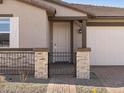 Close up of the front door with stone pillars, brick pathway, gravel, and a two car garage to the right at 17761 W Elm St, Goodyear, AZ 85395