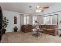 Spacious living room with brown couches, a coffee table, and large windows at 19633 N Marble Dr, Sun City West, AZ 85375