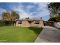 Brick home with a large green lawn, carport, and mature trees at 2112 W Mulberry Dr, Phoenix, AZ 85015