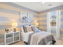 Cozy bedroom with blue and beige striped walls, neutral bedding, and ample natural light at 27256 N 74Th Ln, Peoria, AZ 85383