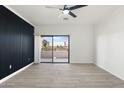 Living room featuring a modern accent wall, fan, light wood floors and sliding glass doors leading to a balcony at 5345 E Van Buren St # 226, Phoenix, AZ 85008