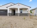 The house features a dark two-car garage and a covered porch with stone pillars at 17697 W Southgate Ave, Goodyear, AZ 85338