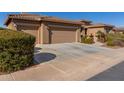 Tan three-car garage house with mature shrubs at 20652 N Wishing Well Ln, Maricopa, AZ 85138