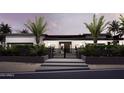 Modern home with a black gated entry, palm trees, and meticulously maintained landscaping at dusk at 11612 N 86Th St, Scottsdale, AZ 85260