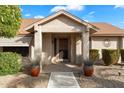 House entrance with tiled walkway, potted plants, and a security door at 20215 N 149Th Dr, Sun City West, AZ 85375