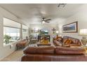 Bright living room with leather furniture, large windows, and a ceiling fan at 10631 W Brookside Dr, Sun City, AZ 85351