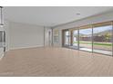 Open-concept living room with wood-look tile floors and a large sliding glass door with covered patio view at 12316 W Parkway Ln, Avondale, AZ 85323