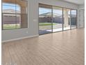 Bright living room featuring wood-look tile floors and large sliding glass doors to backyard at 12316 W Parkway Ln, Avondale, AZ 85323
