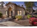 Tan stucco home with arched entryway, landscaping, and walkway at 14300 W Bell Rd # 326, Surprise, AZ 85374